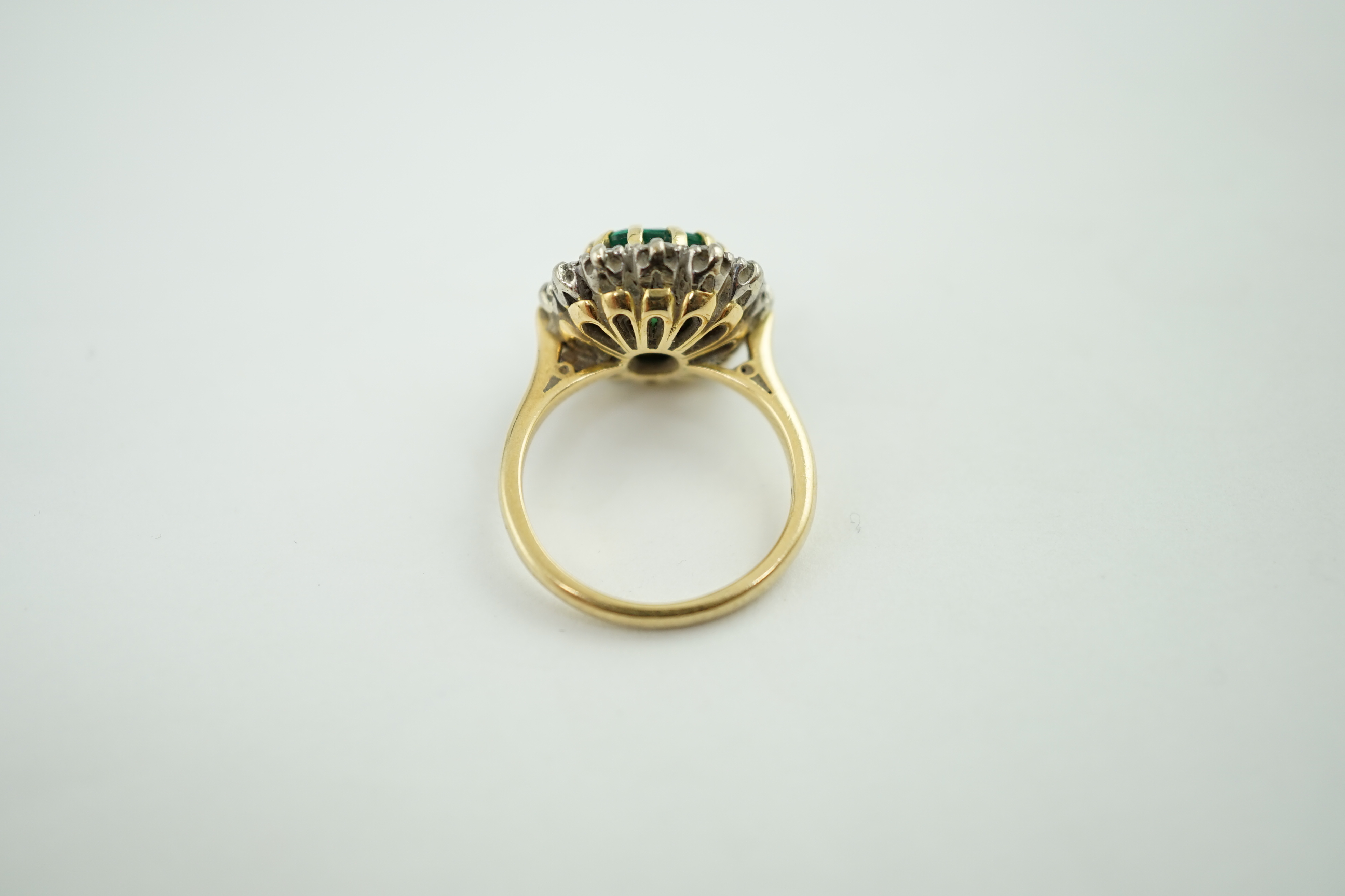 A late 1970's 18ct gold, emerald and diamond set oval cluster ring